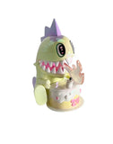 A pastel dinosaur from the tokidoki 20th Anniversary Blind Box by tokidoki (IT) sits by a birthday cake with “20” in pink, tongue out—an adorable addition to any kawaii collectibles shelf.