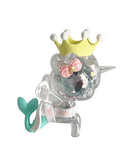 A clear plastic unicorn-mermaid figurine with a teal tail, yellow crown, and pink flowers—perfect for kawaii collectors or fans of the tokidoki (IT) 20th Anniversary Blind Box.