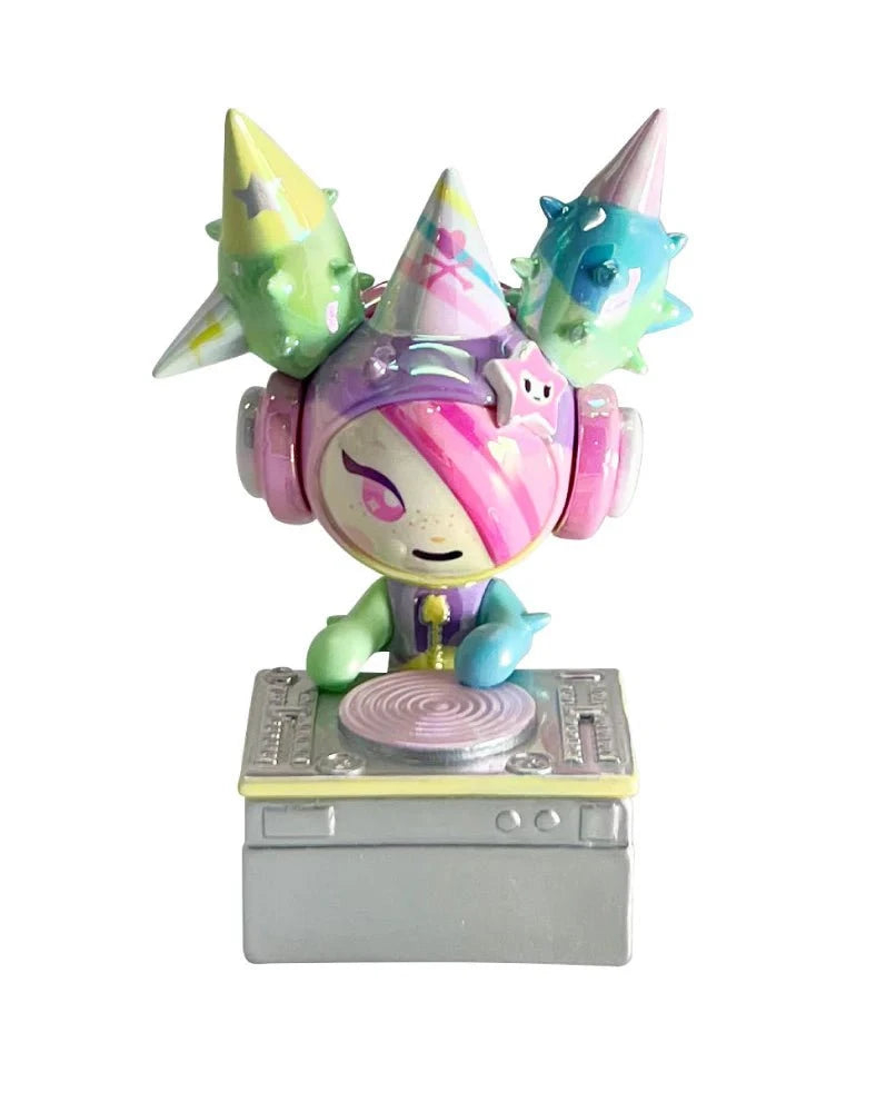 A vibrant DJ figurine with pastel hair, headphones, and spiked party hats stands at a mixer—one of the kawaii collectibles from the tokidoki (IT) 20th Anniversary Blind Box series.