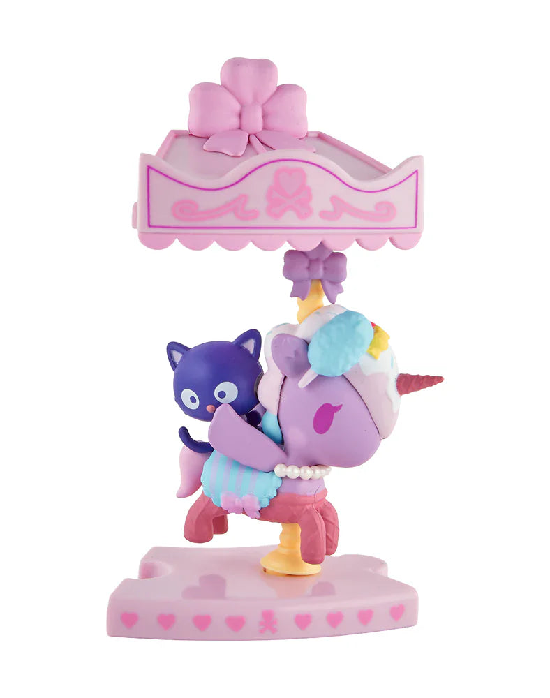 A small pastel unicorn figurine with a purple cat on its back, inspired by the tokidoki x Hello Kitty and Friends Sweet Pink Carousel Blind Box, stands under a pink canopy with a bow on top.