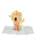 A tokidoki Baby Unicorno Blind Box figure with a yellow mane holds an orange teddy bear on a patterned cloth—a delightful collectible for fans of tokidoki.