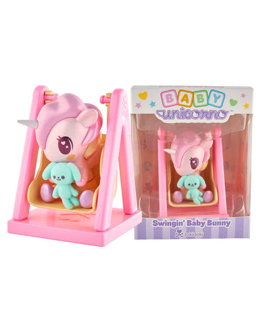 The Tokidoki Baby Unicorno - Swingin' Baby Bunny (Special Edition) features a pink figure with a pastel blue bunny on a swing, shown beside its packaging from the tokidoki Baby Unicorno series.