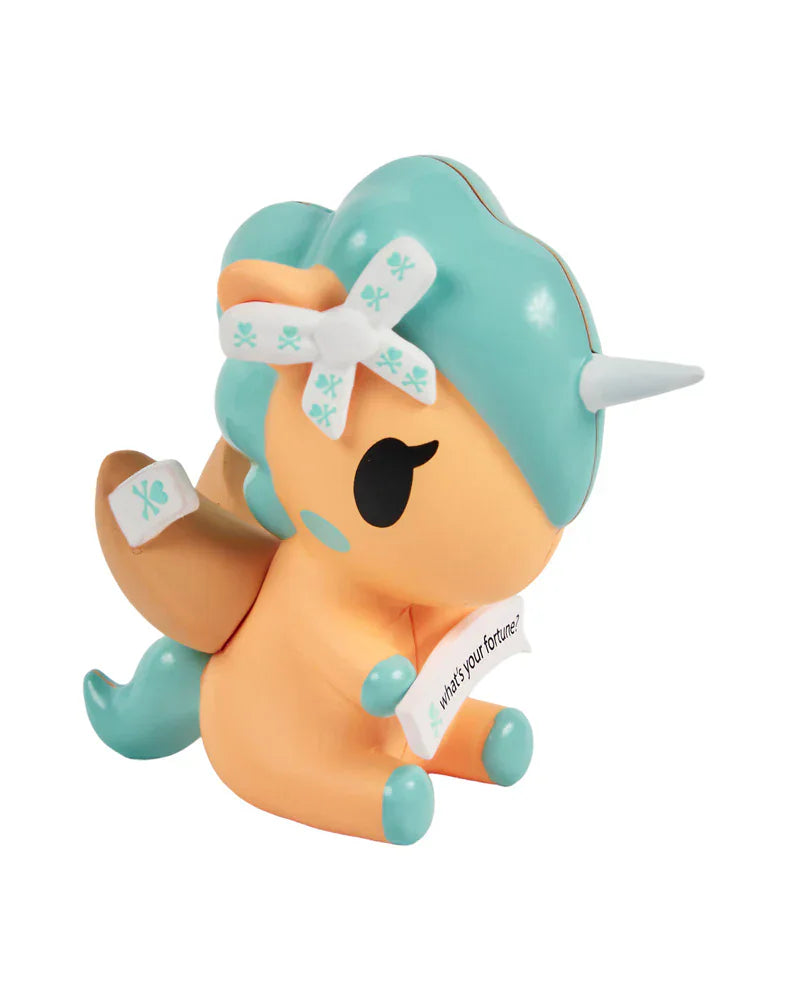 The Tokidoki Fortune Cookie Unicorno Blind Box features a pastel orange and teal figurine with a white horn, bow, wings, and a fortune slip—a charming surprise collectible from the Blind Box series.