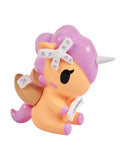 A small orange and purple Tokidoki unicorn figurine from the Fortune Cookie Unicorno Blind Box, featuring a white horn, pink mane, skull and crossbones bows, and holding a white scroll.