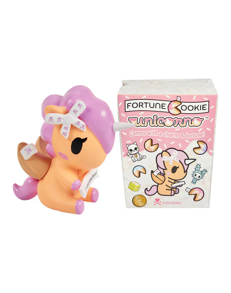 The Tokidoki Fortune Cookie Unicorno Blind Box features a pastel unicorn figurine with fortune cookie details, presented beside its charm-adorned packaging—a delightful surprise collectible for fans.