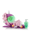 A Tokidoki Spa Day Unicorno Blind Box figurine lies face down on a purple mat with a bear eye mask, towel, and 