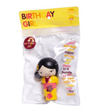 A charming, small handpainted Birthday Girl Momiji Doll made of resin, featuring black hair and a yellow kimono, is encased in a clear package labeled 