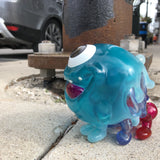 A blue Type-D (Rotofugi Exclusive) toy by Strangecat Toys on the sidewalk.