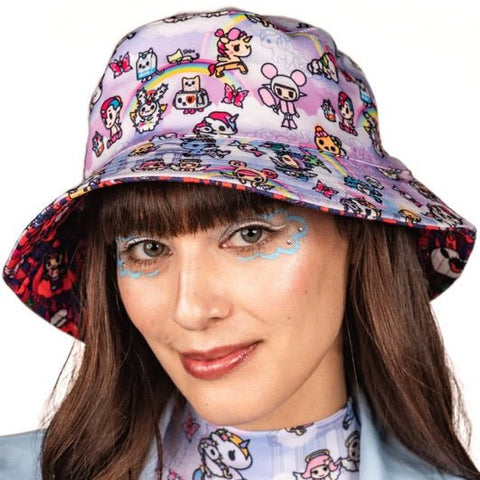 A woman wearing a tokidoki Heavenly Reversible Bucket Hat with kawaii characters on it.