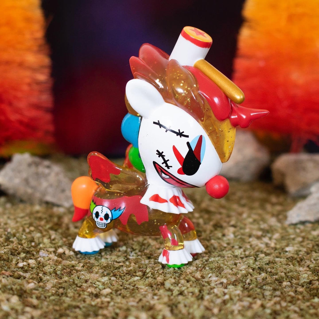A tokidoki Unicorno After Dark Series 2 Blind Box toy with a clown face is standing in a field.