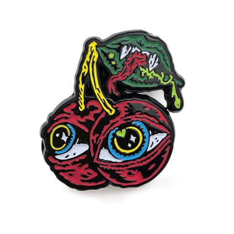 An enamel Cherries Pin by Cherry Moth Cake with an eye and a cherry on it.